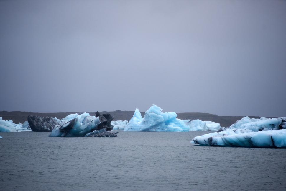 Blue icebergs with grey-gray background of water and sky